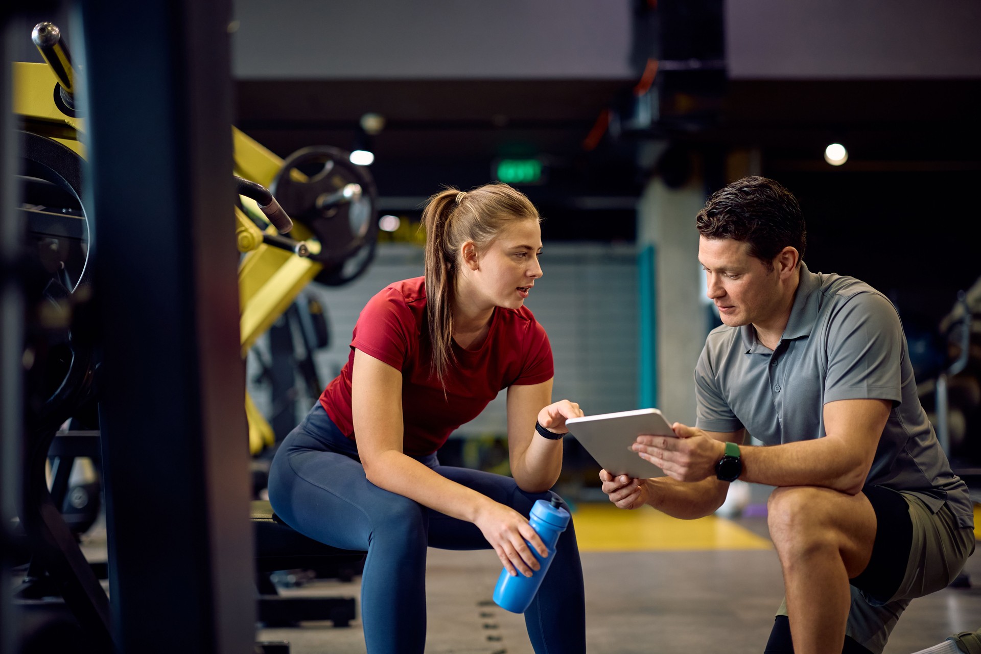 Athletic woman and her personal trainer talking about exercise plans at fitness center.